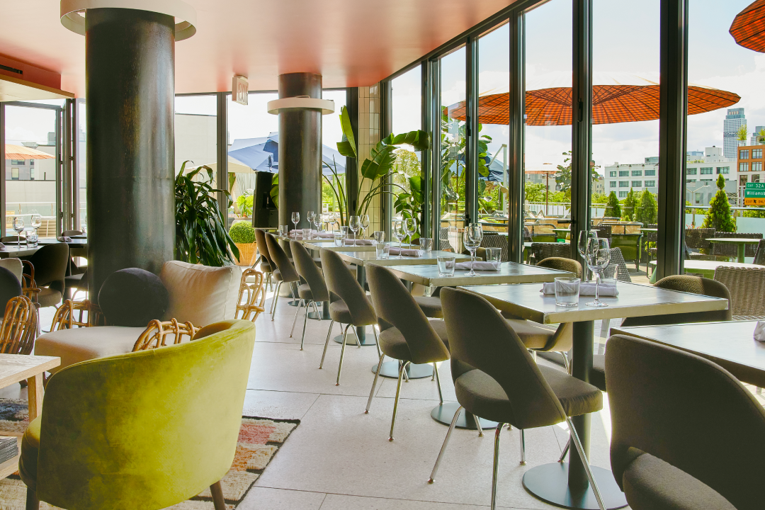 A luxurious event space adorned with hanging flowers and vibrant purple lighting, featuring a stage and mirror-like floor